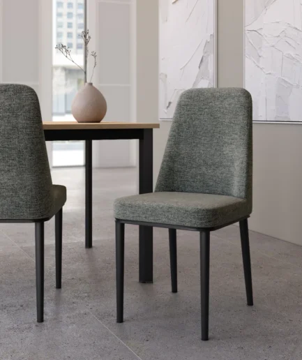 Silla Oslo tapizada en gris claro con patas negras y diseño moderno con respaldo alto.