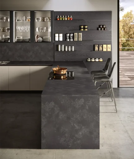 Cocina moderna con puerta Jay, muebles en acabado Ghiaia y Rovere Carbone, vitrinas Diva con vidrio, boiserie decorativa y librería Ever en un espacio abierto de estilo contemporáneo.