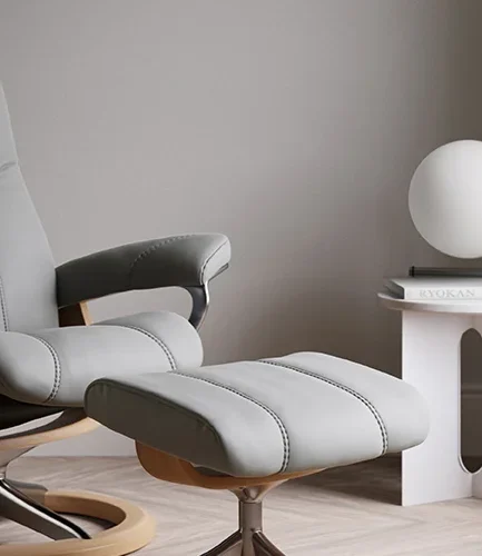 Sillón Stressless® Consul de diseño clásico y elegante, disponible en diferentes tamaños, tapizados y bases, acompañado de un puf reposapiés a juego.