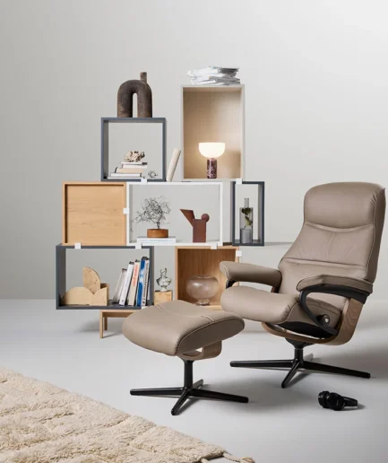 Sillón Stressless® Philip de respaldo alto y diseño envolvente, acompañado de reposapiés y disponible con bases Signature o Cross.